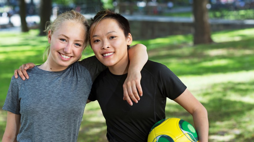 två ungdomar i park med en fotboll