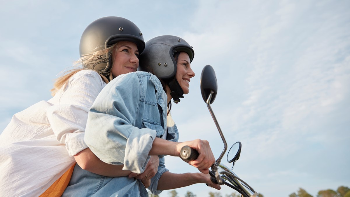 Två tjejer tillsammans på en moped.