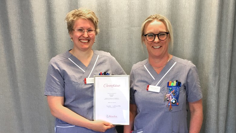 Två sjuksköterskor håller ett diplom